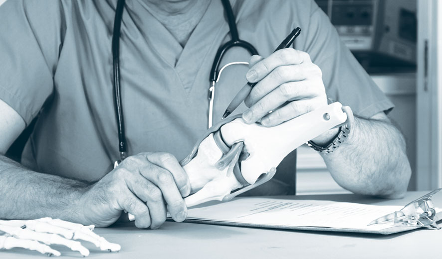 An orthopaedic surgeon illustrating a proposed Knee arthroscopy with a medical model.