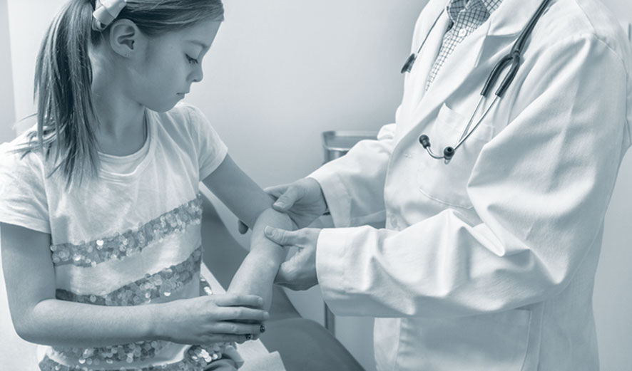  An orthopaedic surgeon diagnosing and treating an orthopaedic problem in the arm of a young girl.